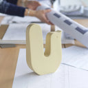 Scultura decorativa | Mira in forma di u, design giocoso in tonalità pastello su un tavolo di lavoro.