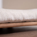 Cuccia per cani e gatti da interno Campero con un comodo cuscino bianco e base in legno.