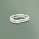 Bracciale flessibile profilo quadrato due giri in argento sterling su sfondo verde.